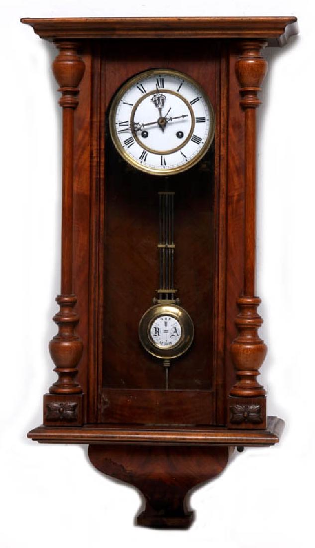 A VIENNA EIGHT-DAY REGULATOR WALL CLOCK: Turned wood half-columns, porcelain enamel dial with Roman numerals, enamel RA pendulum, walnut veneer bracket, time and strike, pendulum patent numbered 55006. Measures 27.25 x 14.25 x 7.25 inches. W