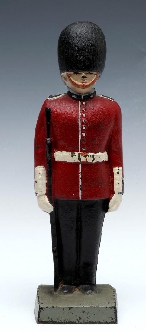 A CAST IRON BRITISH QUEEN'S GUARD DOORSTOP: A three-dimensional polychrome doorstop, solid cast iron construction, unsigned. Measures 9.25 x 2.75 x 2.5 inches. We happily provide seamless in-house packing and shipping services on nearly everyth