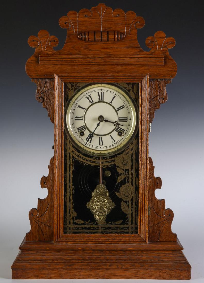 A KITCHEN GINGERBREAD CLOCK ATTRIBUTED E.N. WELCH: A 19th century oak kitchen clock, replacement painted dial with Roman numerals and lettering of E.N. Welch Manufacturing Co, repousse pendulum, eight day, time and strike, signed on the dial, the back