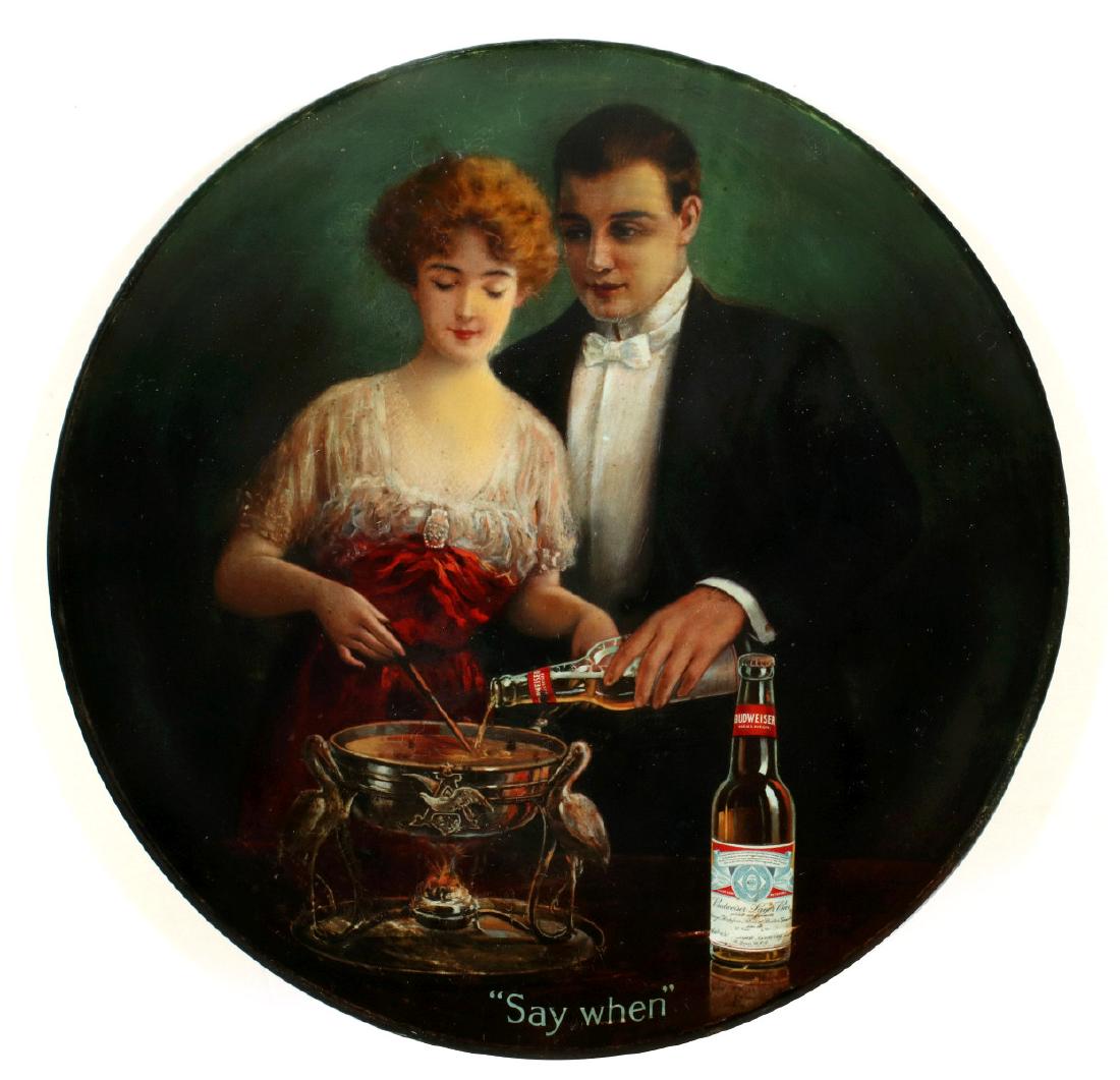 PRE-PROHIBITION ANHEUSER BUSCH BUDWEISER BEER SIGN: The circular convex rolled edge lithographed tin sign features a couple adding Budweiser beer to a chafing dish, titled 'Say When.' Measures 15.5 inches in diameter. We happily provide seamless in-hou