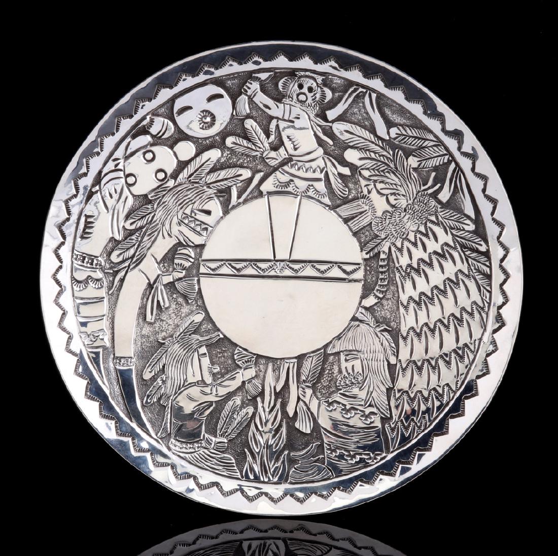 A STERLING SILVER FLOYD BECENTI STORYTELLER PLATE: The Kachina storyteller plate by master Navajo silversmith Floyd Becenti (1962-2016) of Gallup New Mexico depicts a Shalako, a Mud Head and various other dancing kachina figures encircling a shield of