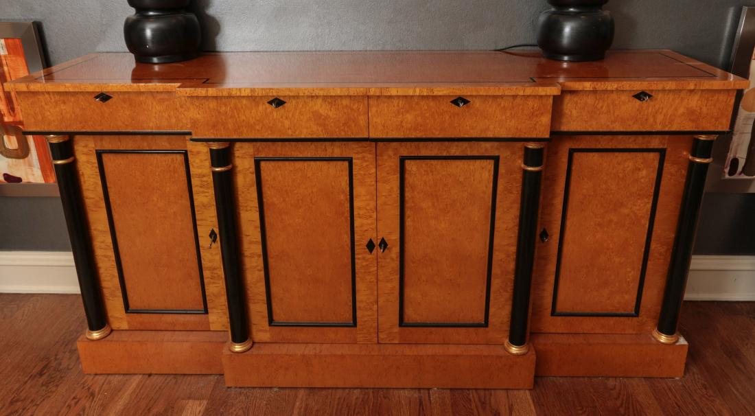 A FINE BURLED BIEDERMEIER SIDEBOARD: The highly figured bird's Eye Maple veneers inlaid and accented with ebonized details, the outset front with ebonized columns either side of two central doors, the overhanging top with two additional 