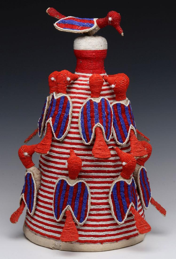 A NIGERIAN YORUBA BEADED CROWN WITH BIRDS: The cloth lined crown covered with figural beaded birds in red, white, blue and yellow. Measures 17 x 10 inches. We happily provide seamless in-house packing and shipping services on nearly everything