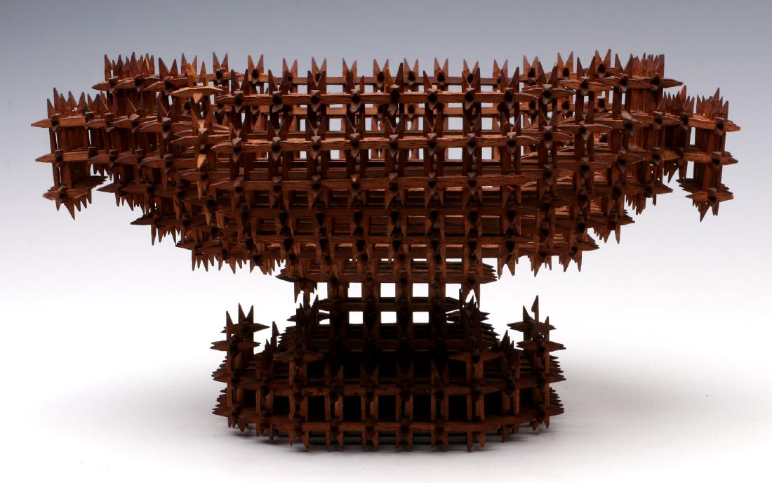 AN EARLY 20TH C. TRAMP ART CROWN OF THORNS BASKET: An exceptionally fine example, super patina, the intricate lattice basketry carved from thin mahogany, an oval bowl-shape form with end handles on stepped base with brackets at each end. Measures 7 x 