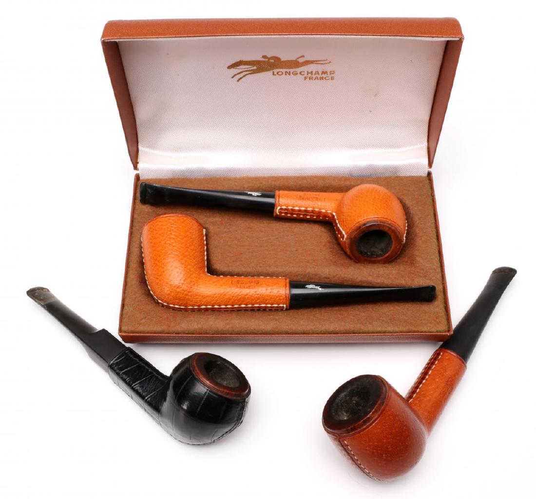 LONGCHAMPS LEATHER-CLAD FRENCH PIPES CIRCA 1960s: Four leather-clad pipes circa 1960, one in black alligator, all signed with impressed marks, two in a branded presentation case. Measure 5.5 to 5.75 inches. We happily provide seamless in-house packin