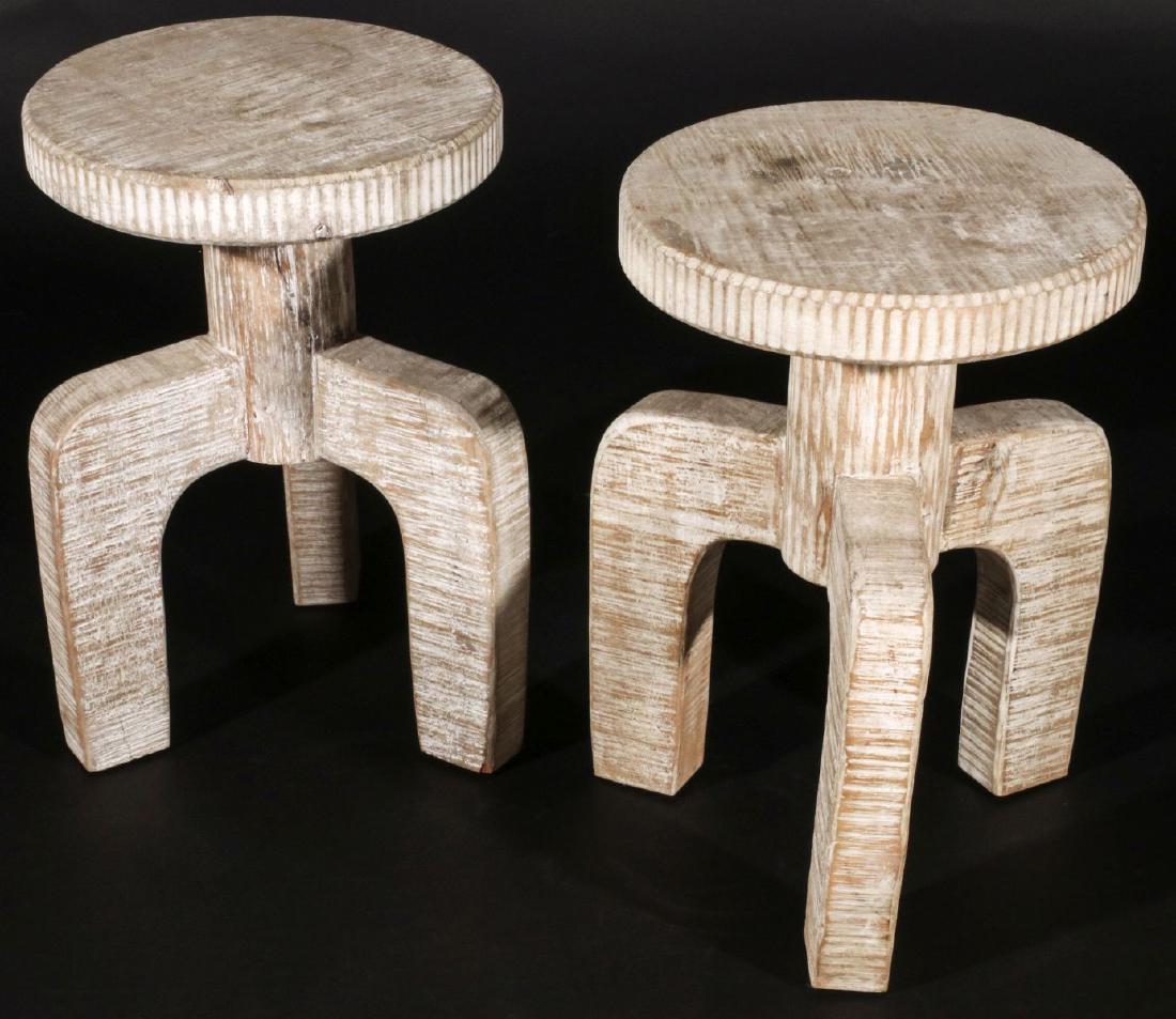INTERESTING PAIR OF CARVED AND PICKLED WOOD STOOLS: The circular tops with coined edge, tripod base with arched legs. Measures 18 inches. We happily provide seamless in-house packing and shipping services on nearly everything we sell.