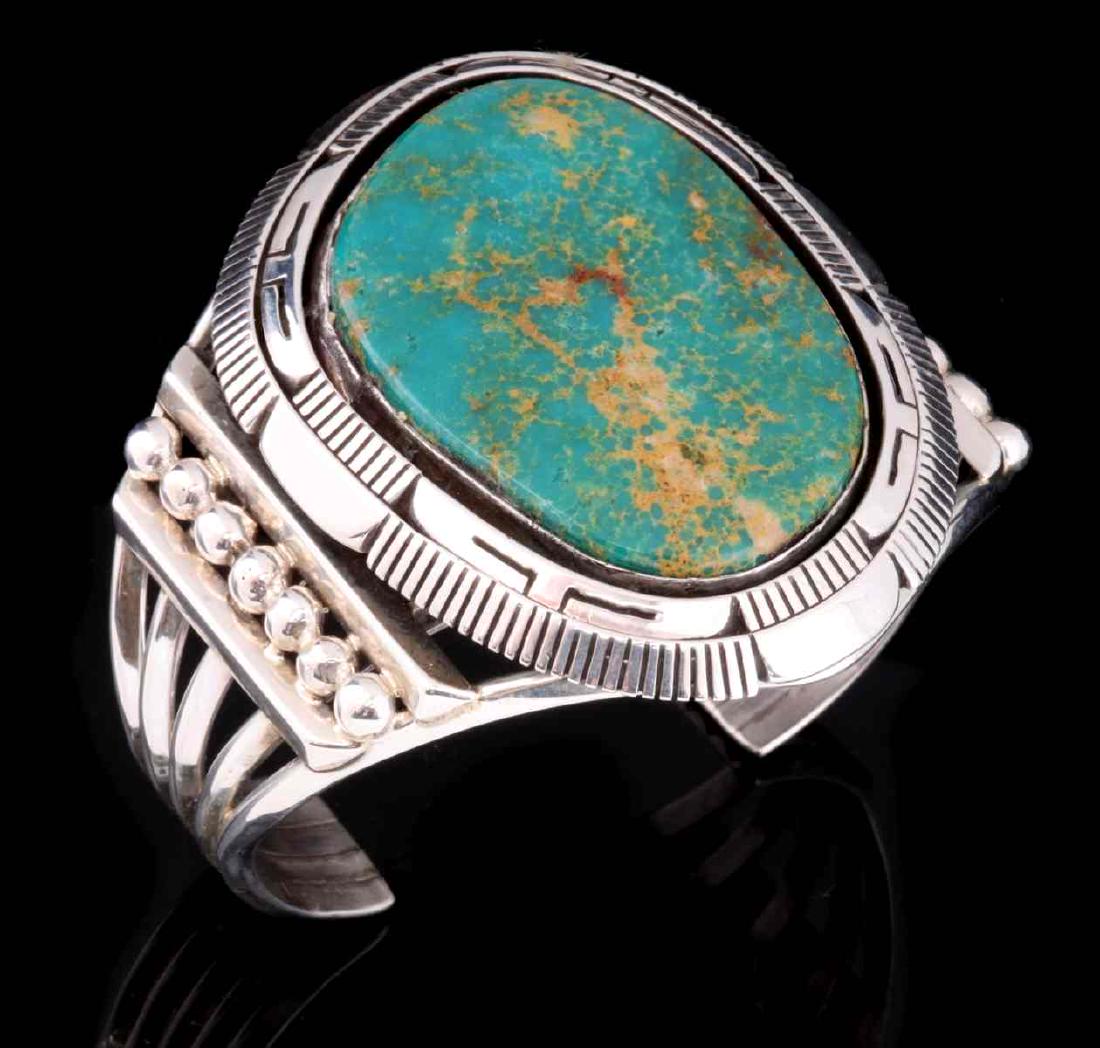 AN ELOUISE KEE MANASSA NAVAJO TURQUOISE BRACELET: The free-form green turquoise stone with brown matrix from the King's Manassa mine in Colorado, framed within thick intricate hand-cut silver bezel, rows of Navajo tears and solid silver bars, all on