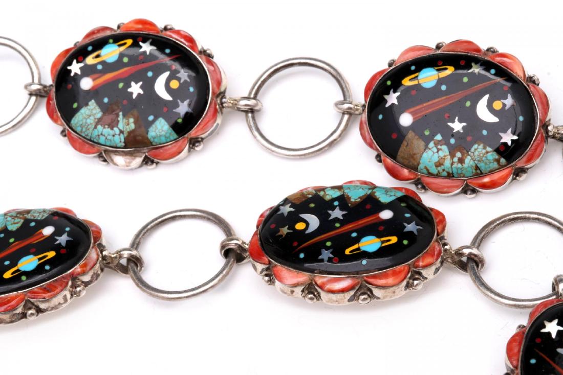 AN UNUSUAL CONCHO BELT INLAID IN THE ZUNI STYLE: An unusual belt comprised of fourteen smaller 'conchos' and matching larger buckle joined by sterling silver jump rings, the galactic theme of each is a depiction of Saturn, the moon, stars and other 