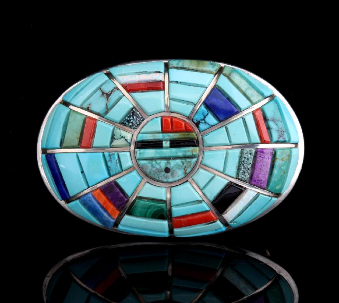 A BRILLIANT ZUNI SUNFACE BUCKLE WITH RAISED INLAYS: A unique oval belt buckle with intricate radiating inlays of turquoise, malachite, opal, coral, lapis, jet and shell stacked in rounded panels divided by thin sterling silver bars as sun rays and cent