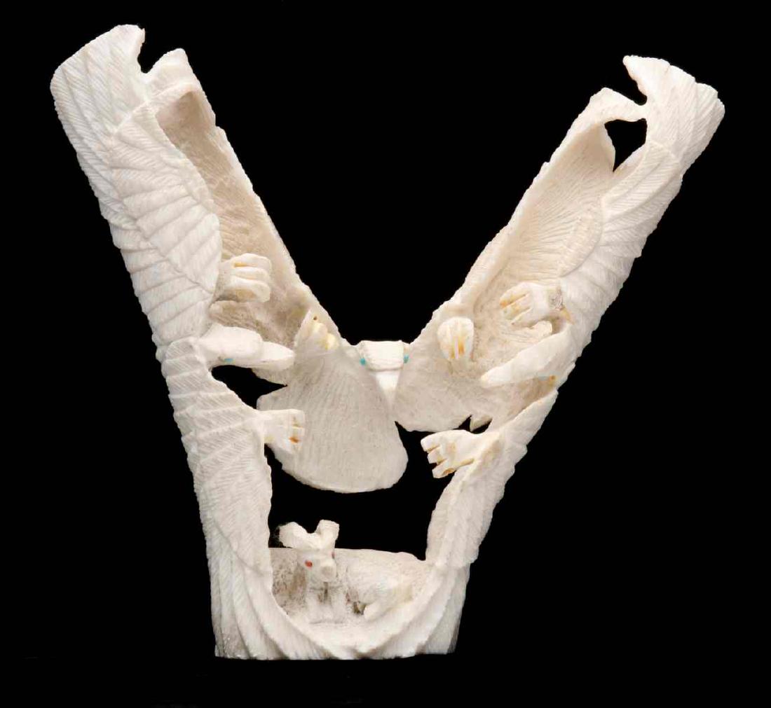 A ZUNI CARVED HORN EAGLE FETISH: The image of three eagles carved from a section of forked antler, a depiction of an attack on a fawn with coral inlaid eyes, each eagle inlaid with turquoise eyes, attributed to Jerrold Lahaleon. Meas