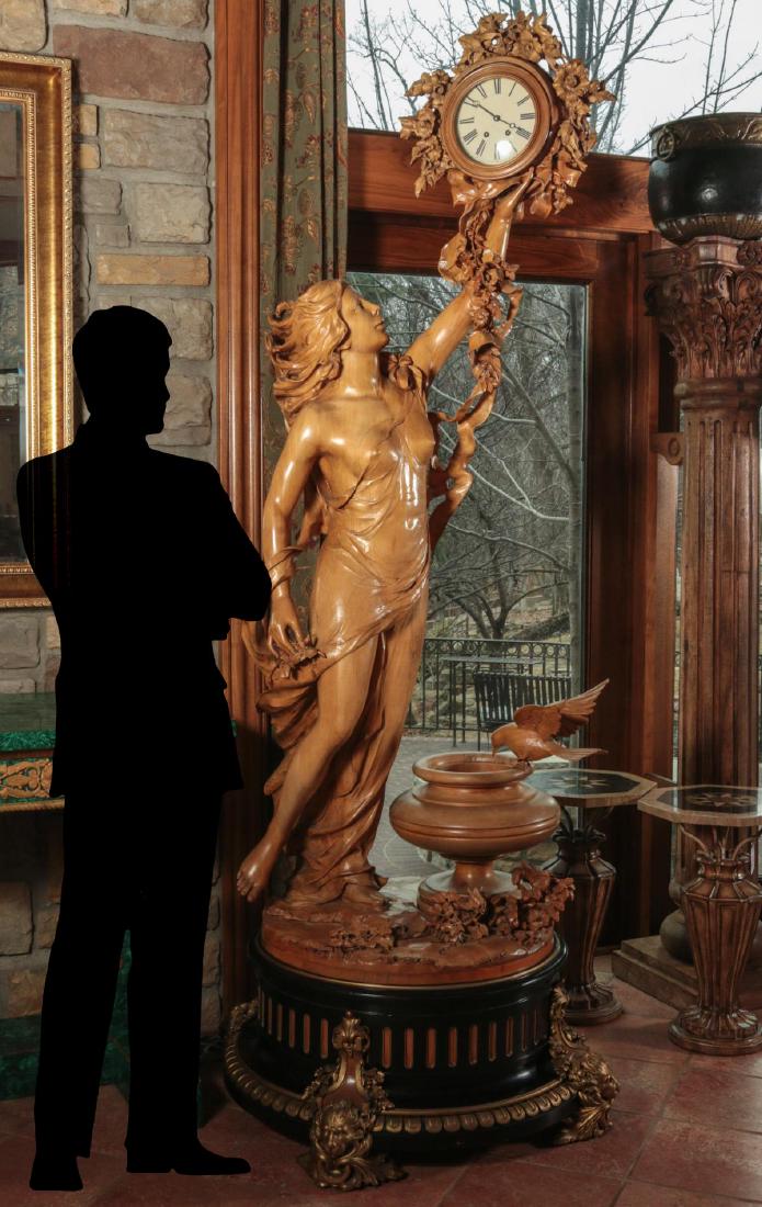 A LIFE-SIZED CARVED FRUITWOOD FEMALE STATUE CLOCK: An astounding Continental carved fruitwood statue clock, the classical maiden in flowing robe and flowing hair standing near an urn with dove on naturalistic base and holding aloft a time and strike t