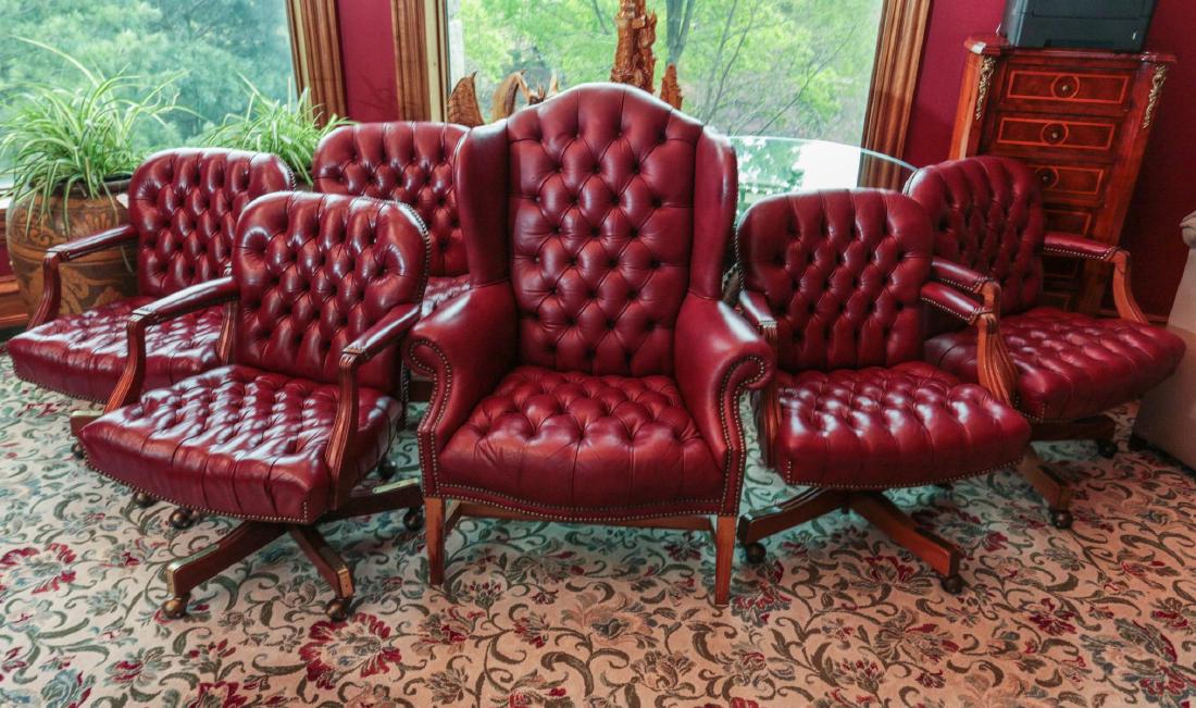 RED LEATHER SWIVEL ARM CHAIRS & MATCHING WINGBACK: A suite of office or conference room chairs, five matching swivel base rolling chairs in button tucked red leather, plus a similar wing back chair. Measures 43.5 x 35 x 30 and 34.5 x 24.5 x 27 inches.