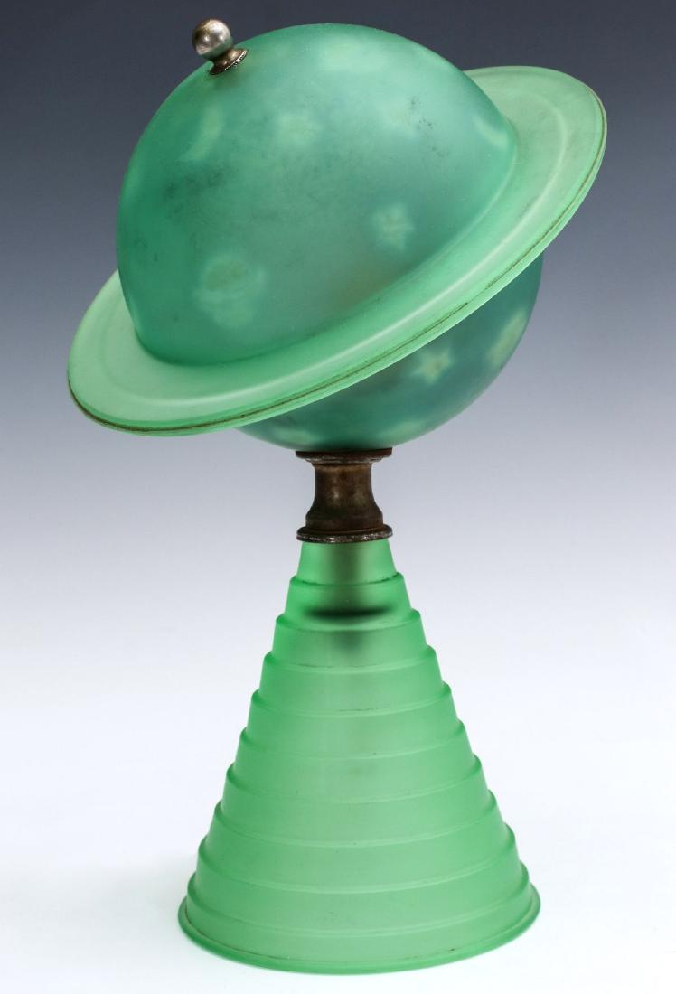GLASS 1939 WORLD'S FAIR PLANET SATURN TABLE LAMP: The green frosted glass planet shaped globe with reverse painted stars and glass ring on stepped conical base. Fluoresces under UV light. Measures 11 x 7.5 inches. We happily provide seamless in-house
