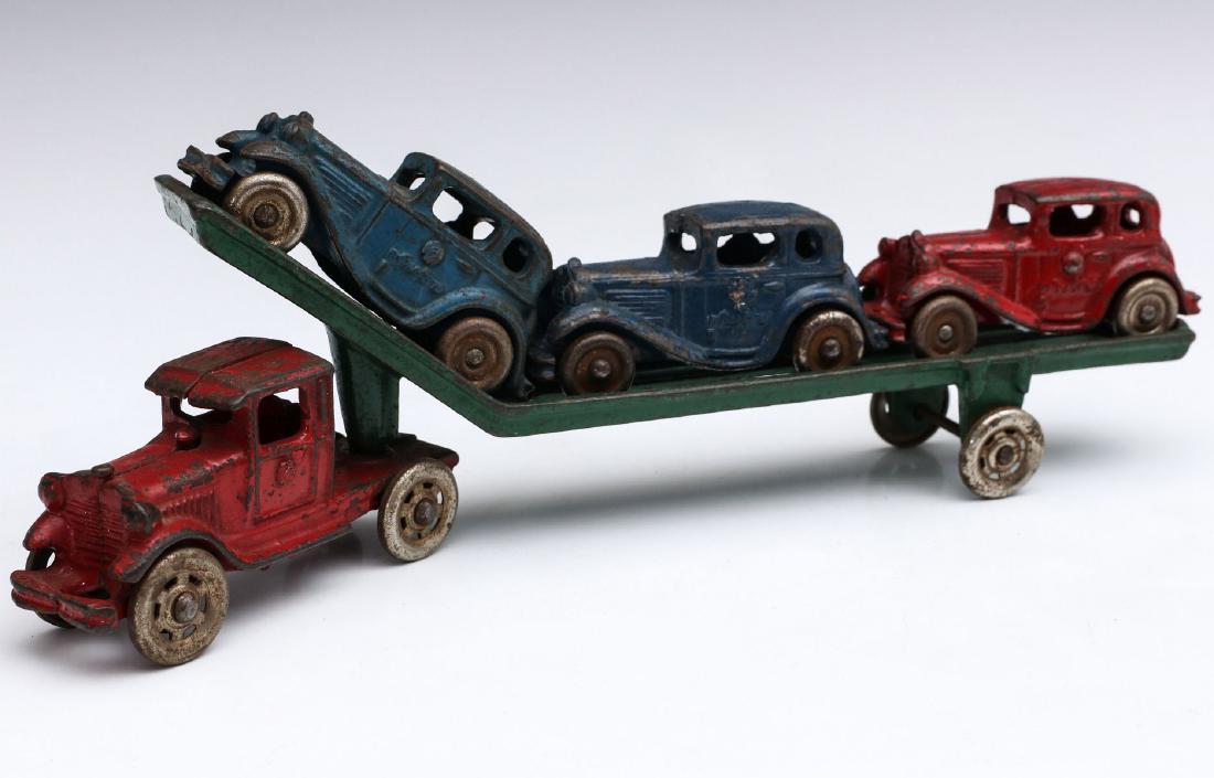 CAST IRON TOY TRANSPORT WITH THREE AUSTIN SEDANS: A circa 1930s car carrier / transport pulled by a 1930s truck, the trailer loaded with three Austin sedans, attributed to A.C. Williams Company, Ohio. Measures 4 x 12.75 x 1.5 inches. We happily provi