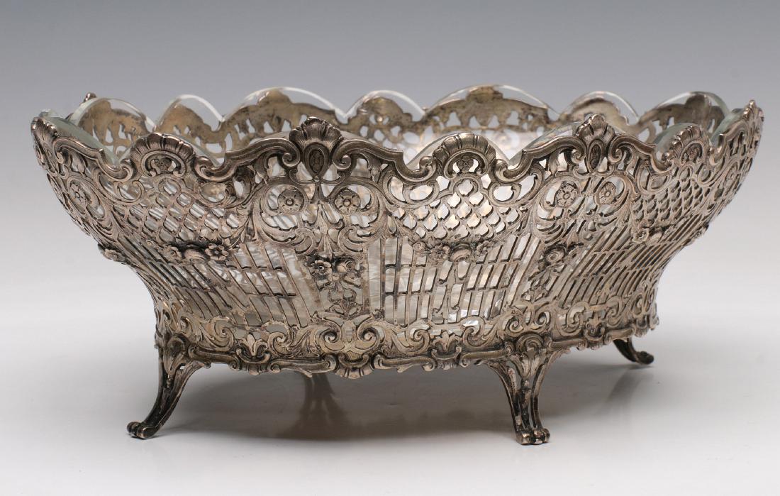 A CONTINENTAL .800 SILVER BASKET WITH GLASS LINER: The Rococo style .800 silver filigree basket with scalloped glass liner (crack) with stamped markings on the base. Measures 4.25 x 10.75 x 7.75 inches. Silver weight without the glass insert is 17.45 