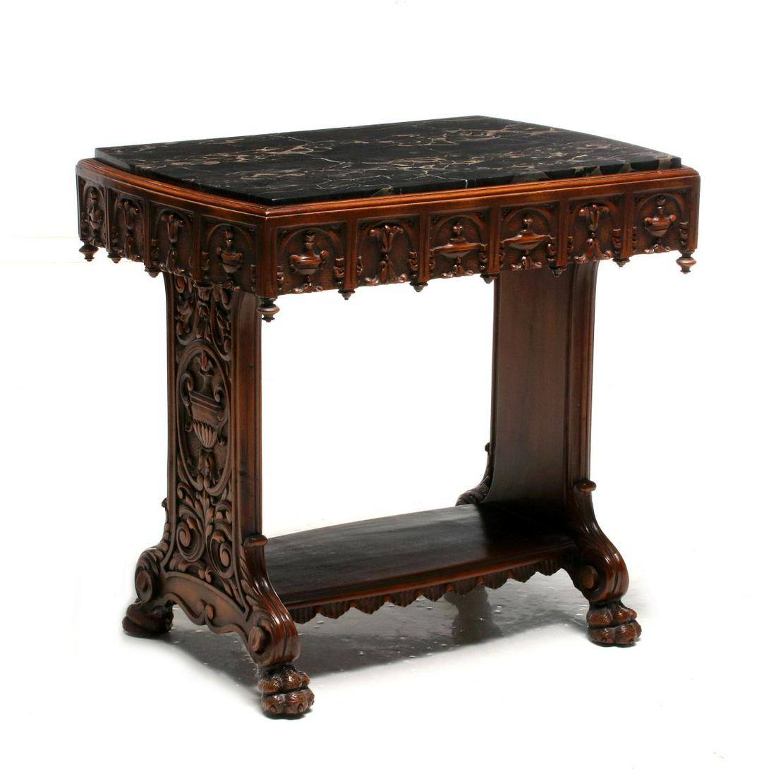 AN EARLY 20TH CENT CARVED SIDE TABLE WITH BLACK MARBLE: The shaped black marble in walnut frame with carved frieze and drop finials, carved ends joined by a wide, flat lower stretcher, raised on four paw feet. Measures 22 x 23.5 x 16.5 inches. We happily p