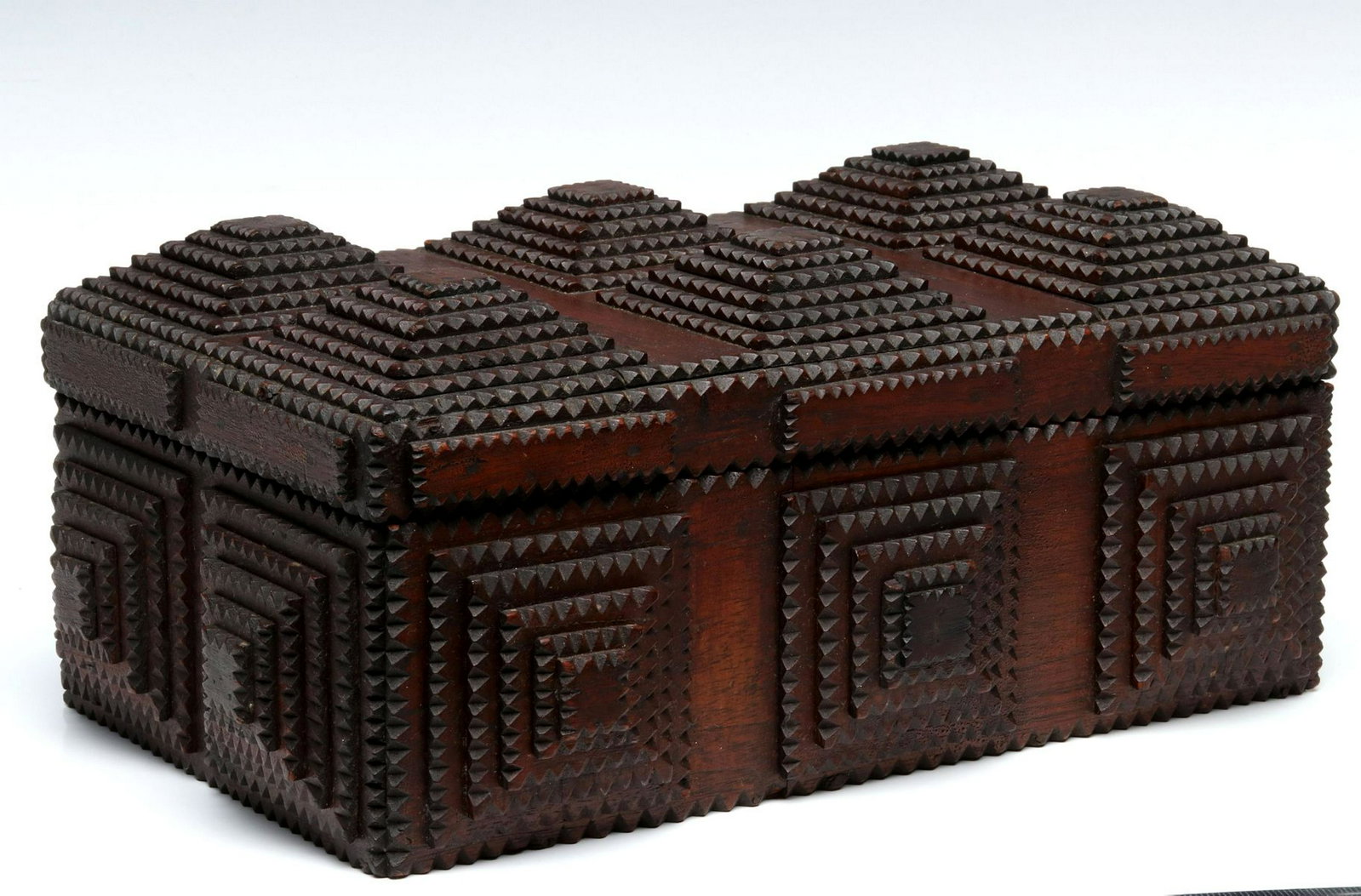 A LARGE AND COMPLEX ANTIQUE TRAMP ART BOX: The box with hinged lid stacked with multiple layers of chip carved slabs in tapering stacks, great dark patina. Measures 7.25 x 14 x 8.5 inches. Provenance: The 45-year collection of Michael and Donn
