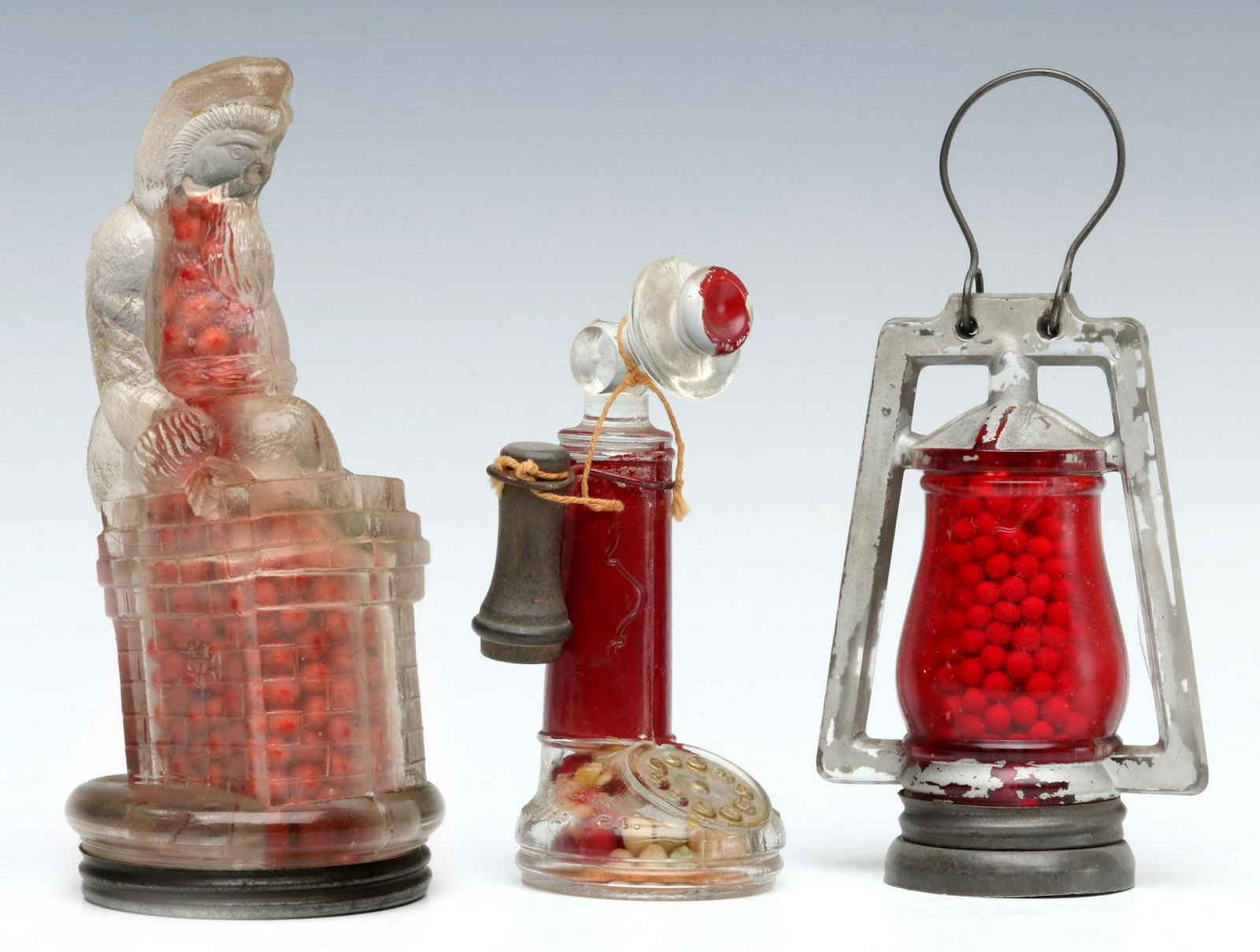 SANTA CLAUS AT CHIMNEY AND TWO OTHER CANDY CONTAINERS: Santa, Lantern and Candlestick Phone, each with original type candy. Measures 5 to 6.25 inches. Provenance: The 45-year collection of Michael and Donna Hayes, West Plains, Missouri. We happily provide