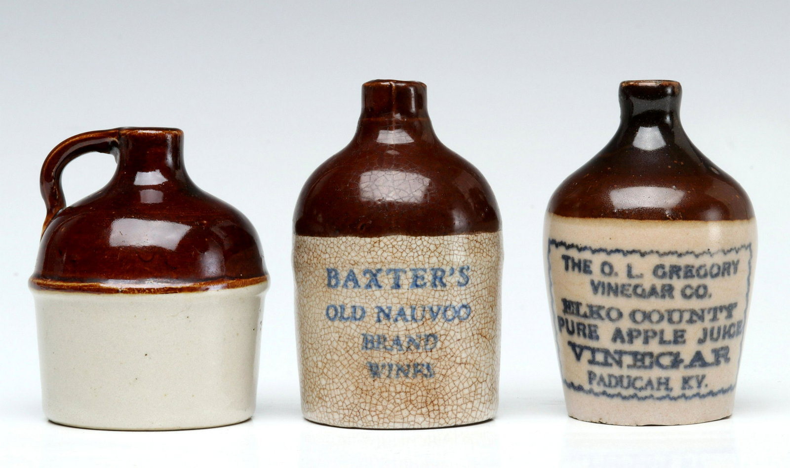 A RED WING MINI JUG WITH TWO ADVERTISING MINI JUGS: The unsigned Red Wing example offered with another advertising Baxter's Old Nauvoo Wines and Gregory Vinegar. Sizes range from 2.75 x 2 to 3 x 2 inches. Provenance: The 45-year collection of Michael a