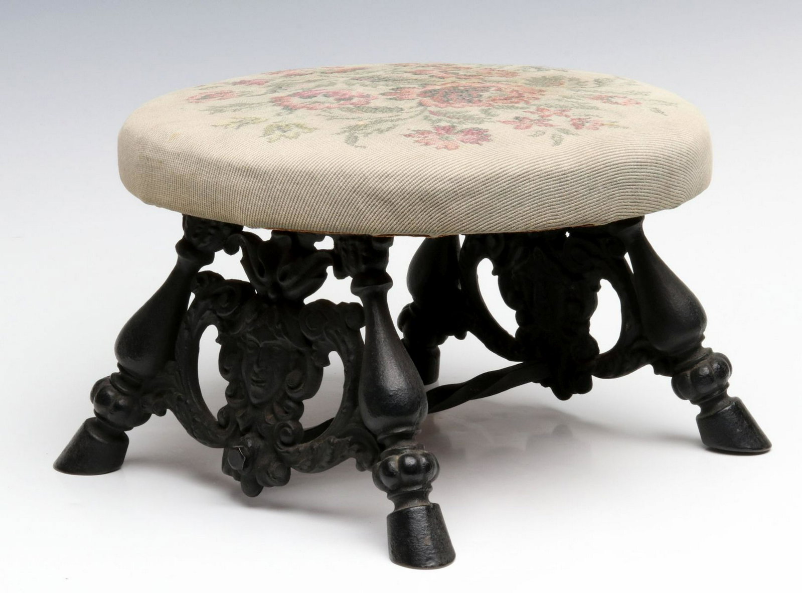 AN ORNATE EARLY 20TH CENT STOOL WITH CAST IRON BASE: The cast iron supports with ladies' heads among scrolls, hoof feet. Measures 7.5 x 11 inches. Provenance: The 45-year collection of Michael and Donna Hayes, West Plains, Missouri. We happily provide s