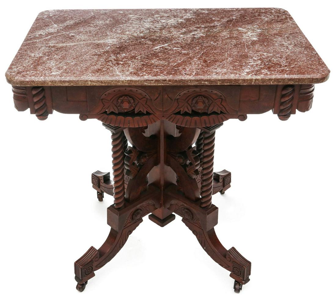 A DISTINCTIVE BROOKS QUALITY VICTORIAN MARBLE TOP TABLE: The rectangular top on conforming wood skirt with rounded corners, applied rope twist carvings, burled veneers, rosettes within carved arching valances with burl, and openwork swags, the four-column b
