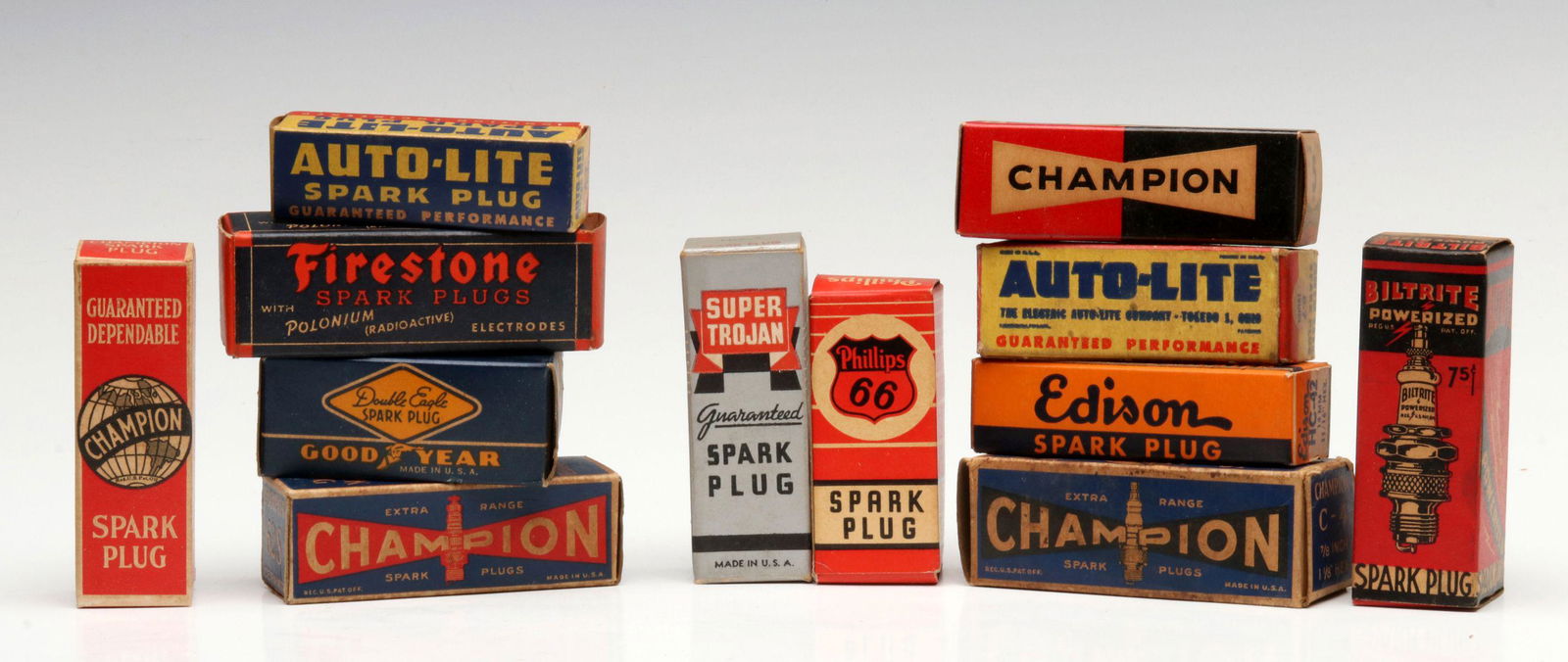 A COLLECTION OF VINTAGE SPARK PLUGS IN ORIGINAL BOX: The collection of twelve in their original boxes: Champion R-7-B; Auto-Lite A-7 14mm; Good Year Double Eagle 56; Phillips 66 P-18-1; Super Trojan No. 4 Hot; Firestone M-40-F; Edison HC-42 14mm 11/16-i