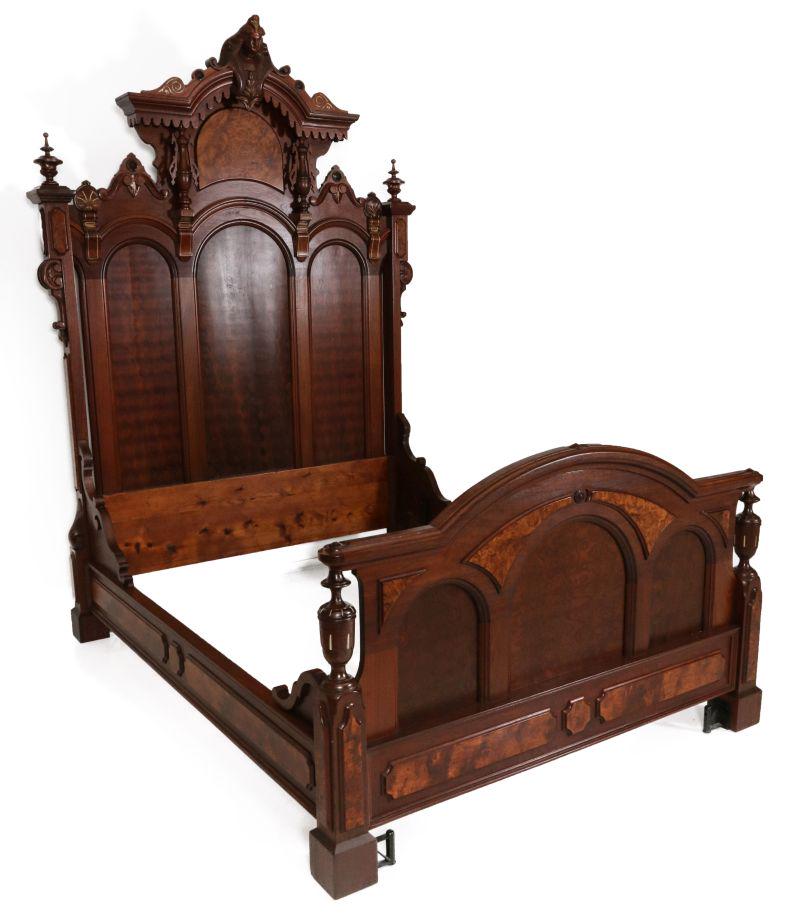 AN EXCEPTIONAL MASSIVE WALNUT BED W/ EGYPTIAN HEAD: The triple arch headboard flanked by urn form finials and carved stiles, surmounted by an elaborate arched and canopied pediment centering a carved Egyptian head on baluster supports embellished with 