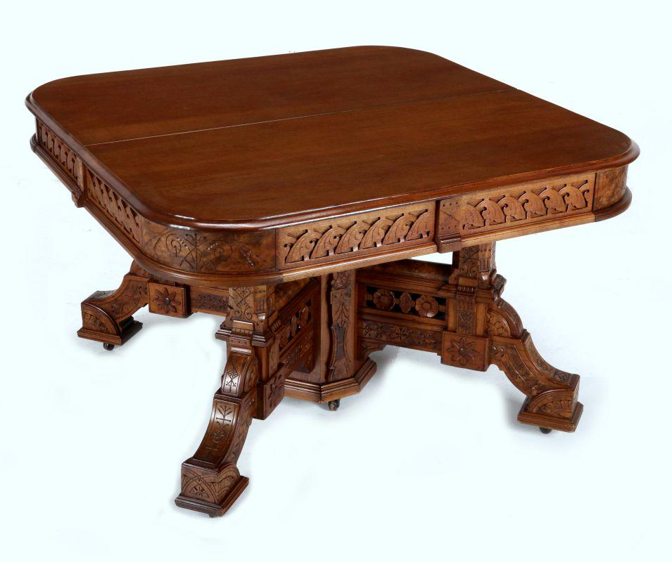 AN OUTSTANDING, MASSIVE WALNUT DINING TABLE TO 8': Rectangular molded top with rounded corners over a frieze of carved entrelac stylized leaves and incised burled corners, octagonal paneled pedestal base issuing squared bracket supports with incised d