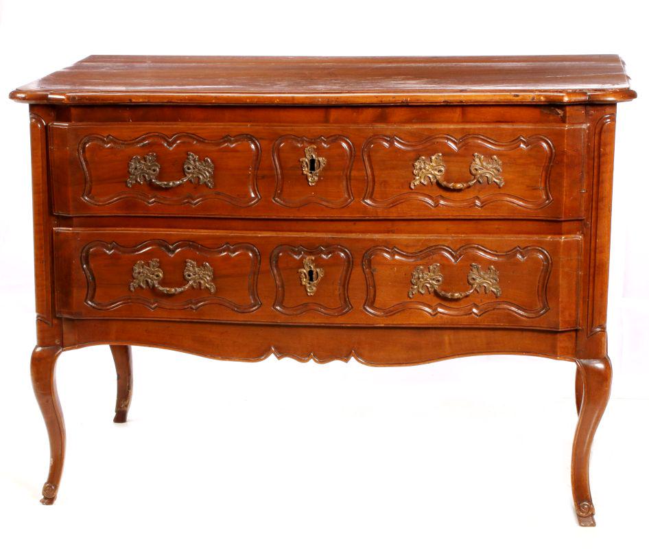 AN 18TH CENTURY COUNTRY FRENCH TWO-DRAWER COMMODE: The shaped overhanging top over two drawers with carved reserves, paneled ends, cabriole legs. Measures 34.5 x 48 x 25 inches. We happily provide seamless in-house packing and shipping services on nea