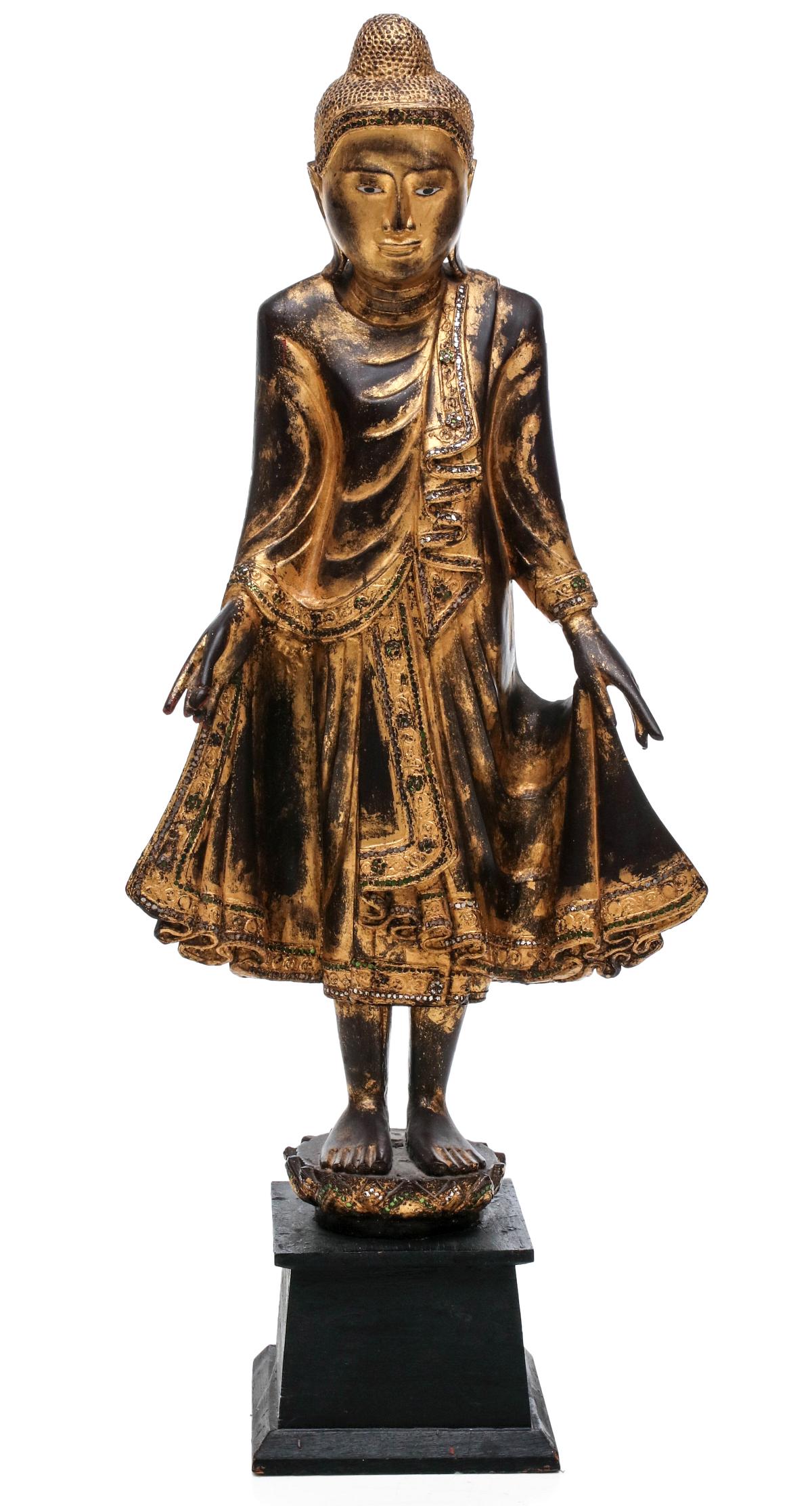 A 41-INCH CARVED, GILDED AND JEWELED FIGURE OF BUDDHA: The carved and gilded wood full length figure standing upon on lotus and dressed in carved flowing robes, mounted on an ebonised wood plinth. Measures 41 x 16.5 x 9 inches. We happily provide seamless