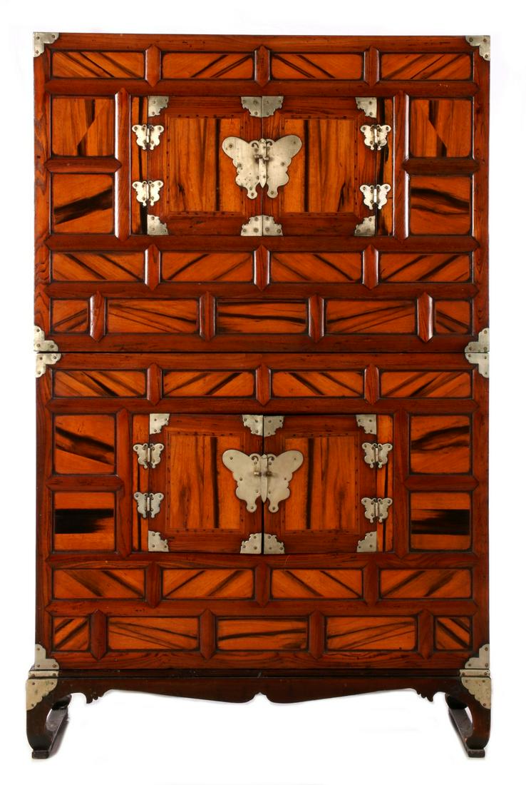 A TALL, HIGHLY FIGURED 19TH CENTURY KOREAN TANSU CHEST: The two-piece cabinet with nickel mounts on highly figured persimmon woods, multiple divided exterior panels, two central doors centering each section, raised on frame with bracket feet joined by stre