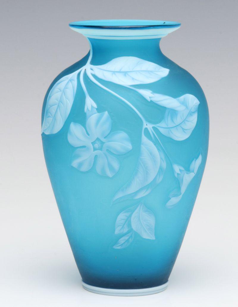 A CAMEO GLASS VASE WITH PERIWINKLE FLOWERS ATTR WEBB: The manner of Thomas Webb, unsigned, white Periwinkle flowers on flowing stems in relief against a satin blue ground. Measures 6 x 3.5 inches diameter. We happily provide seamless in-house packing and