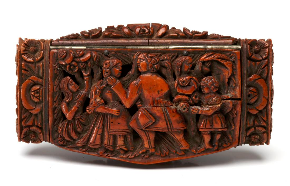 A 19TH CENTURY HEAVILY CARVED TAGUA NUT SNUFF BOX: The hinged cover with five figures, both children and adults, in high relief, the back side a depiction of figures, some in classical robes, within a rectangular frame, the ends and sides of the conta