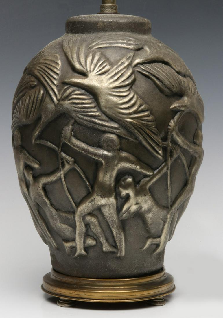 AN ART DECO TABLE LAMP WITH ARCHERS CIRCA 1930s: The patinated composition body molded with large birds (of prey?) and stylized nude archers in high relief, the original faux oxidized finish, original base, hardware and silk wrapped cord. Measures 2