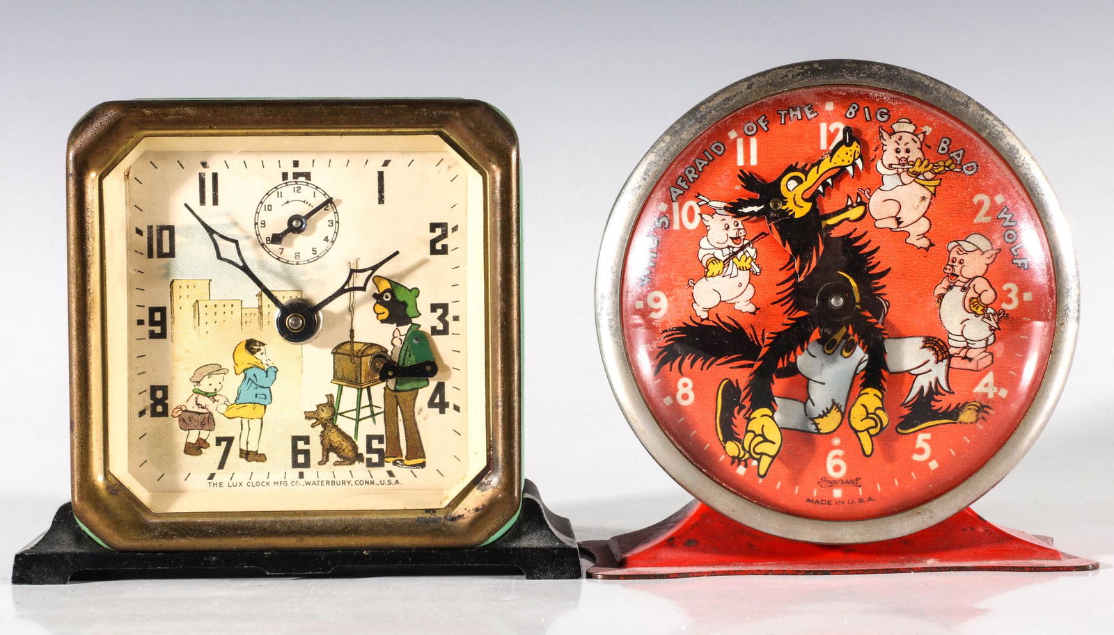 LUX AND WATERBURY MECHANICAL CHARACTER ALARM CLOCKS: The Lux alarm clock with animated street organ grinder, plus an Ingersoll animated clock characterizing The Big Bad Wolf, each circa 1940. Measures 4.75 x 4.5 x 2 and 4 x 4.75 x 2.5 inches. We happily