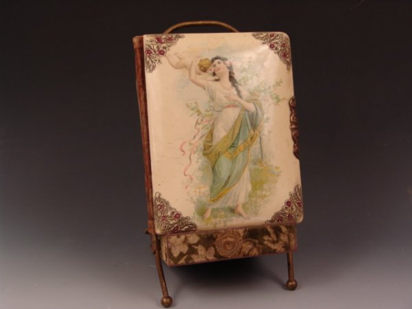 OLD CELLULOID PHOTO ALBUM WITH STAND: This Victorian photo album has a celluloid front and velvet covered back. The front design shows a lady in classical dress with a cherub. The album measures 10 1/4" tall by 8" wide and is 2 1/4" deep.