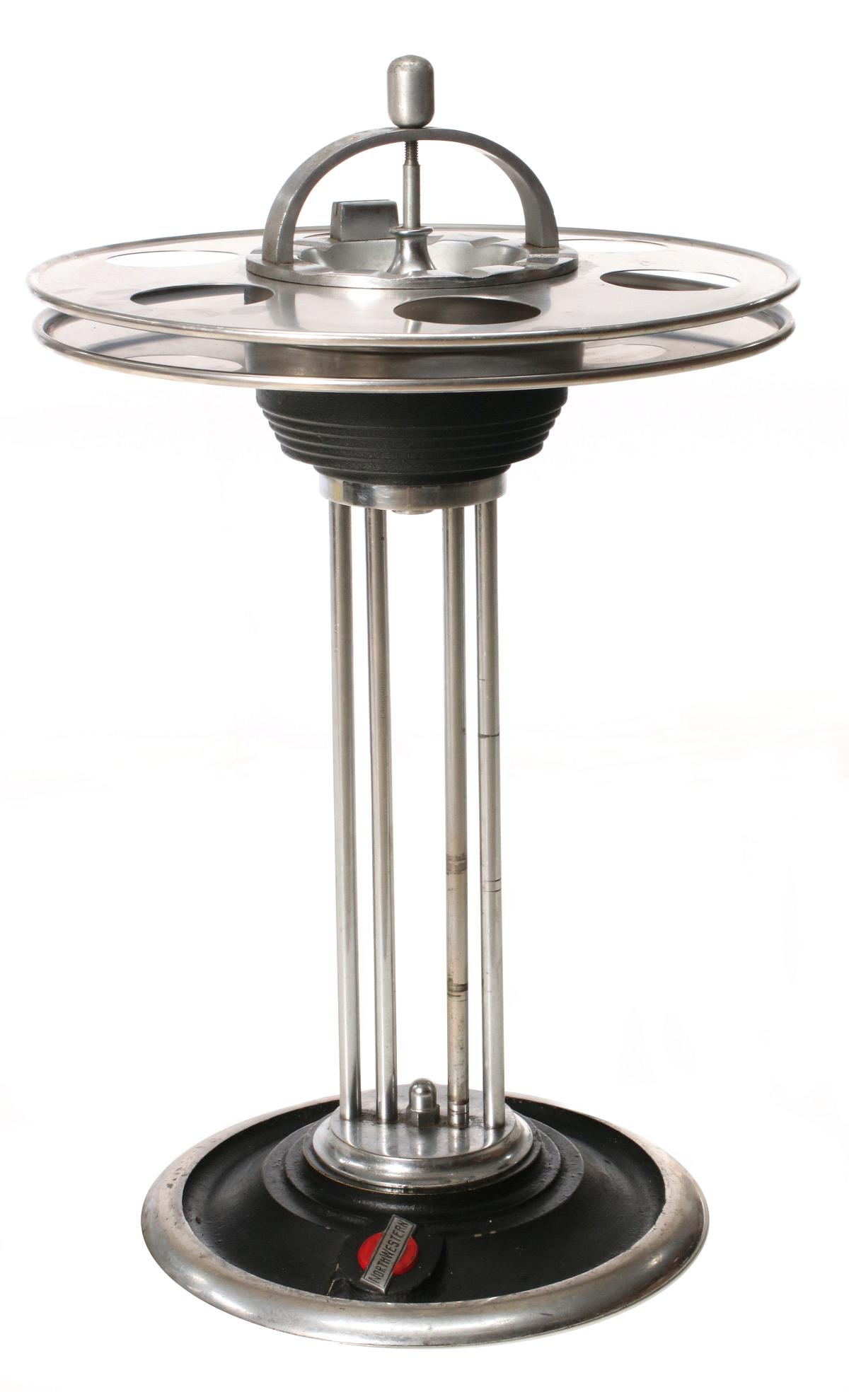 A NORTHWESTERN RAILROAD FLOOR STANDING ASH RECEIVER: The two-tier brushed stainless steel trays with drink holders, central ash receiver with plunger, chromed steel support rods, nickel plated base with black enamel and NORTHWESTERN logo for Chicago & N