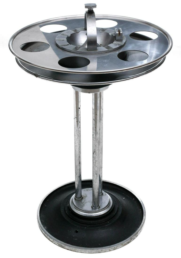 AN UNMARKED ART DECO RAILROAD LOUNGE CAR SMOKE STAND: The two-tier top rings with drink holders, central ash receiver with arched handle, three chromed rod supports raised on domed crinkle finish circular chrome base. Measures 26 x 16 inches. Provenance: