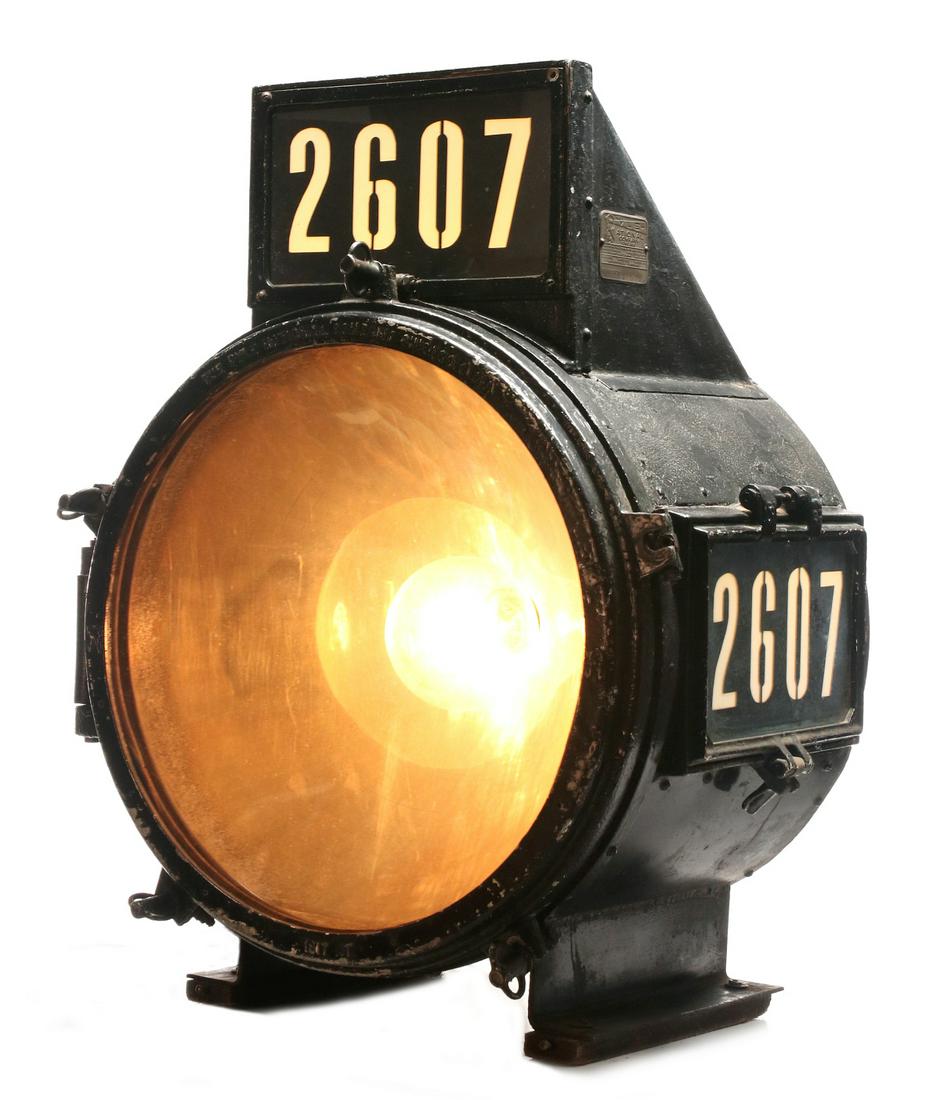 A PYLE NATIONAL STEAM LOCOMOTIVE HEADLIGHT: The cast iron and sheet metal headlight housing with conical convex reflector, standard embossed cast iron markings and lighted number boards atop the headlight along with swept back wing number board