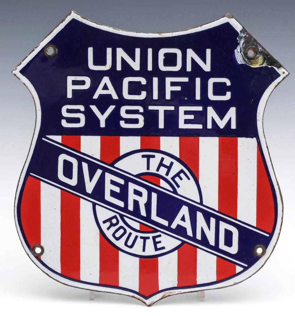 A UNION PACIFIC SYSTEMS OVERLAND ROUTE PORCELAIN SIGN: The red, white and blue die-cut shield-shape porcelain enamel sign with the Union Pacific Systems logo from 1914 to 1932. Measures 10 x 9 inches. Provenance: The Collection of Ed McHugh, Massillon, Oh