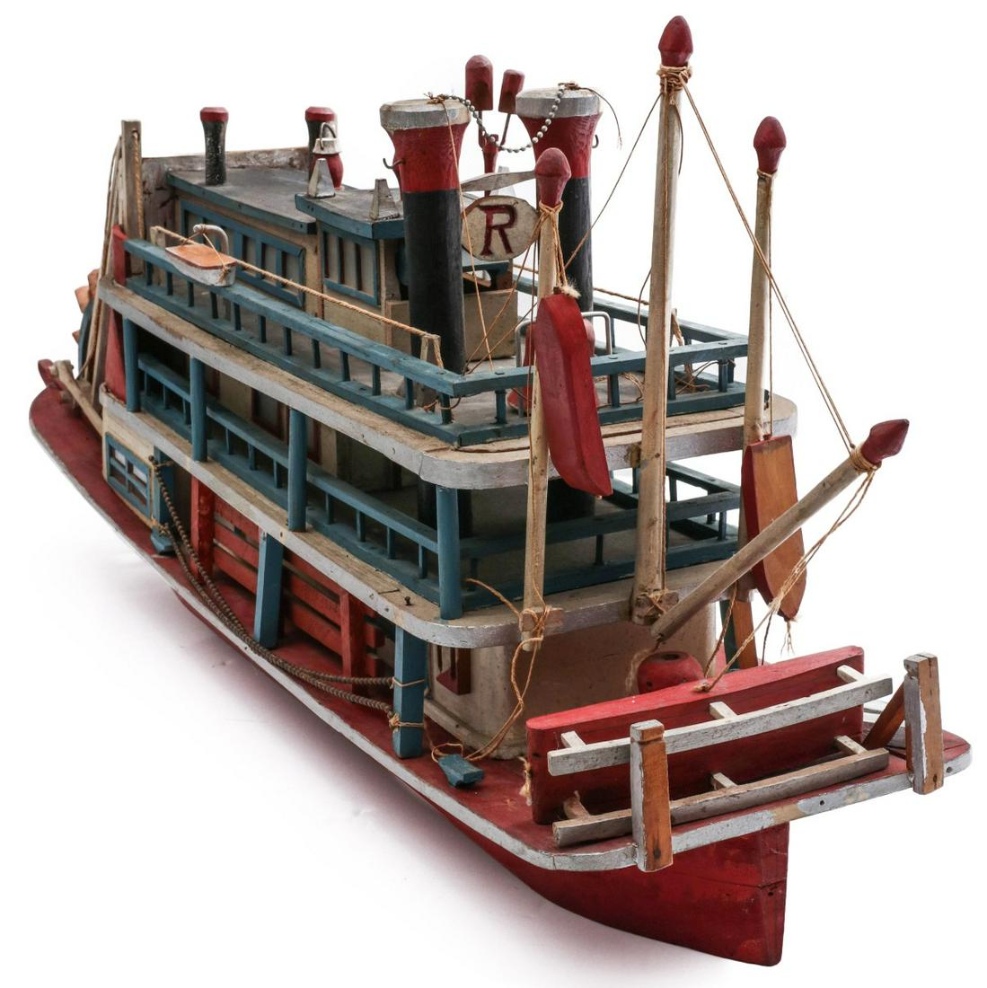 A FOLK ART MODEL OF PADDLEWHEEL RIVERBOAT CIRCA 1950: The detailed folk model carved from wood and painted in red, white, blue and green, the back end lettered in graphite 'RHODA. O.F. RACINE OHIO.' Measures 14 x 29 x 7.75 inches. Provenance: The Collect