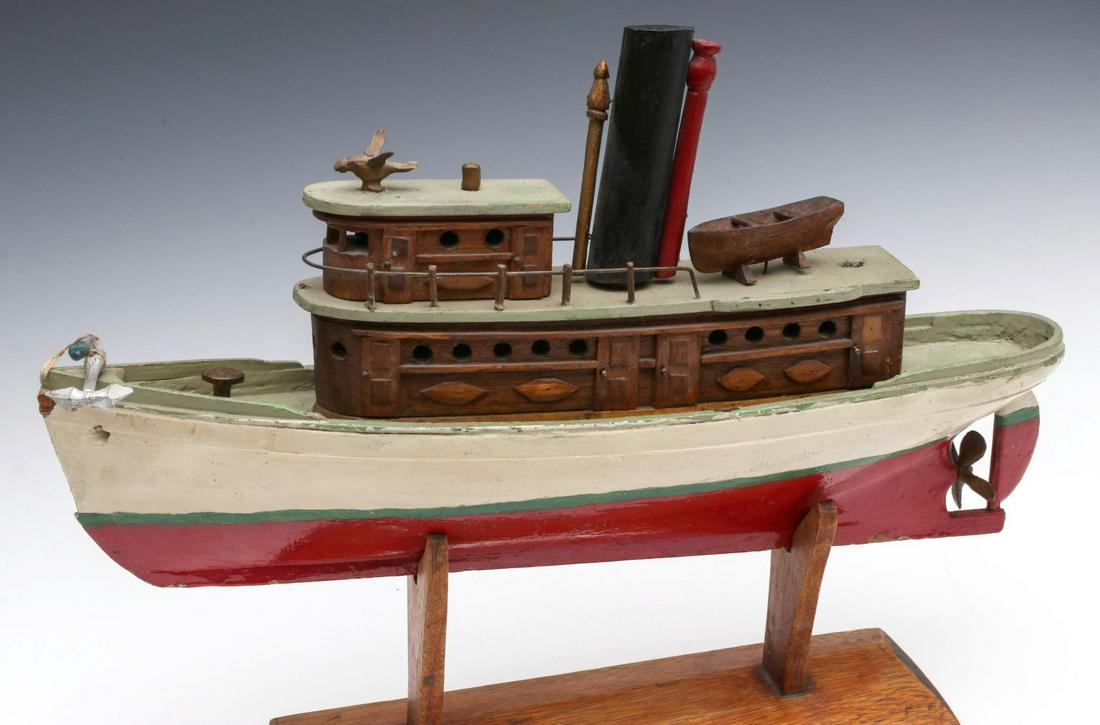 A PAINTED WOOD FOLK ART TUG BOAT, MANNER OF BILL RAU: The folky hand carved and painted steamship tugboat model in four colors and with natural wood elements, circa 1930s. Measures 14 x 18 x 4.5 inches. Provenance: The Collection of Ed McHugh, Massillon,