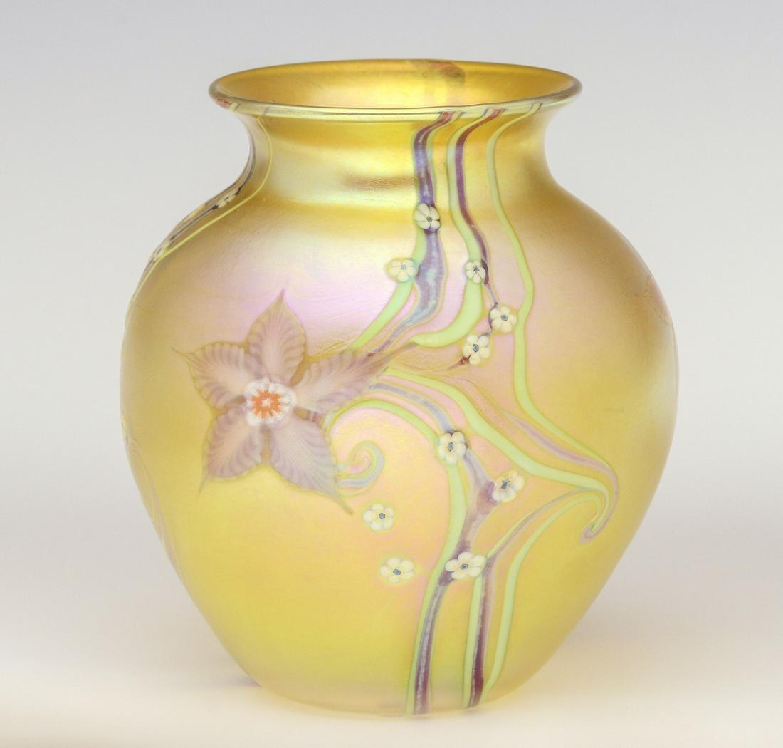 A FINE INLAID ART GLASS VASE SIGNED ORIENT AND FLUME: Late 20th Century. The bulbous vase with flared rim in light gold iridescent finish and small inlaid white flower heads and large blossoms among trailing sinuous vinery, engraved signature and paper l