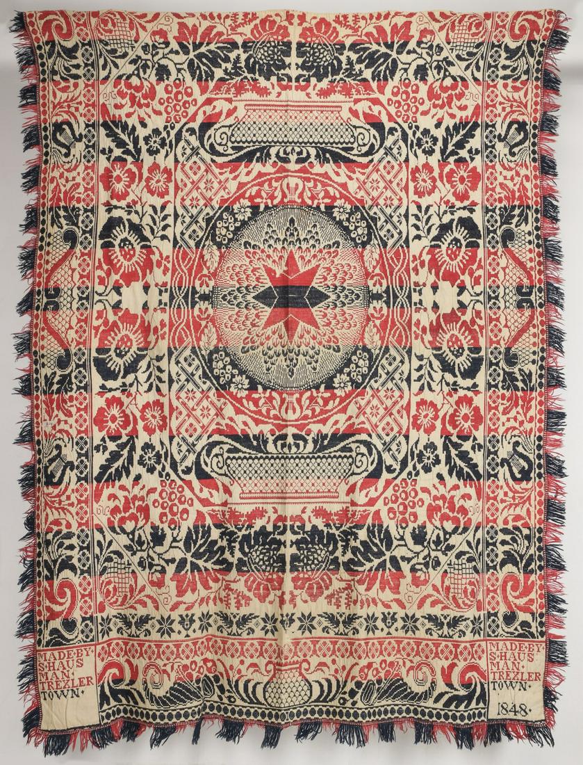 A THREE COLOR 1848 HAUSMAN OF TREXLER, PENN. COVERLET: The red, blue and cream Jacquard coverlet with a central compass surrounded by florals and foliage, woven signature blocks read MADE BY S HAUSMAN TREXLER TOWN 1848 lower left and right. Measures 95 x 