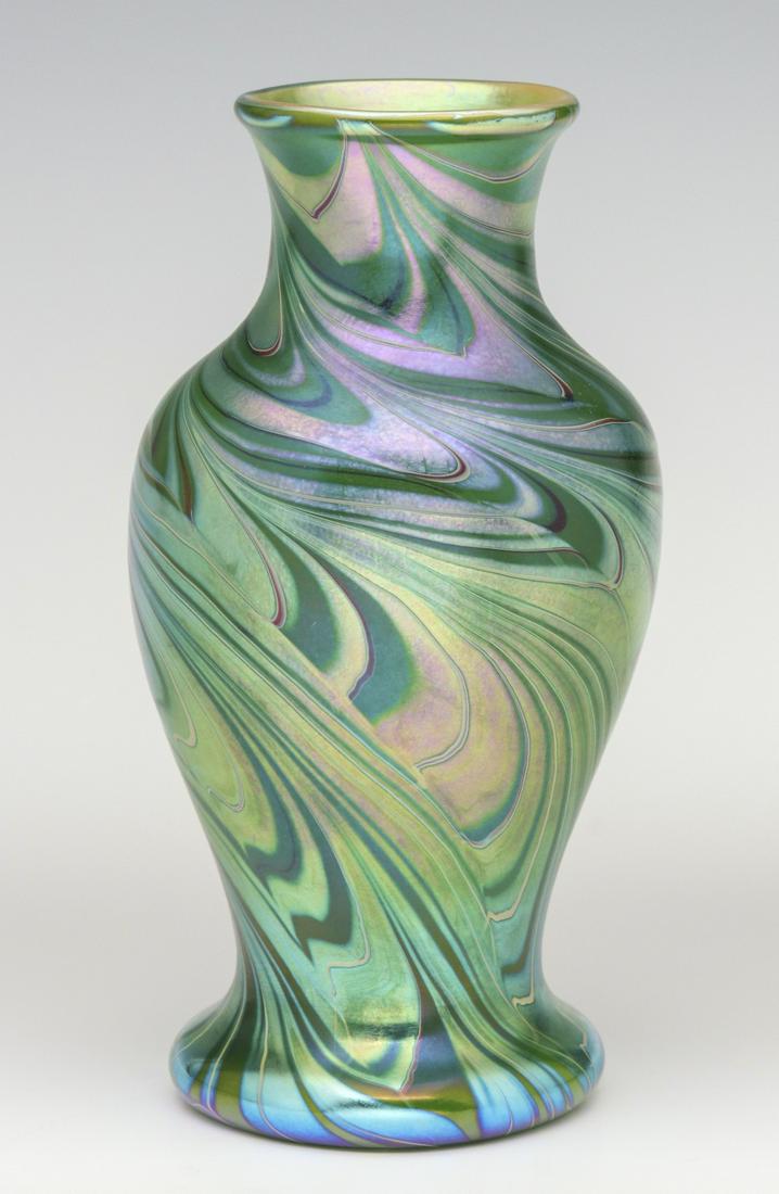 A BALUSTER FORM ART GLASS VASE SIGNED ORIENT AND FLUME: Late 20th Century.The baluster form with flaring foot, pulled iridescent finish with hues of lavender, green, gold and blue.We happily provide seamless in-house packing and shipping services on nearly