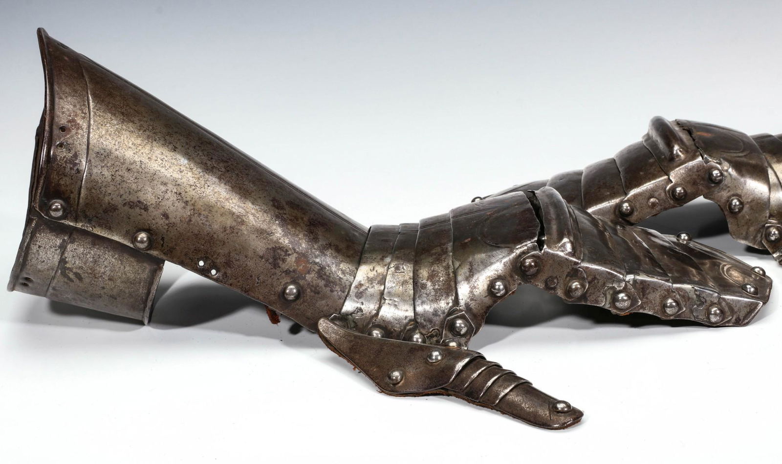 A PAIR LARGE ARMOR BRIDLE GAUNTLETS CIRCA 15TH CENTURY: Each with incised line decoration, hinged thumb, pronounced rib at the knuckle line, forearm cuff. Measures 16 x 5.25 x 5.75 inches. Provenance: The Russell Stover Candy family estate, Kansas City, Mi