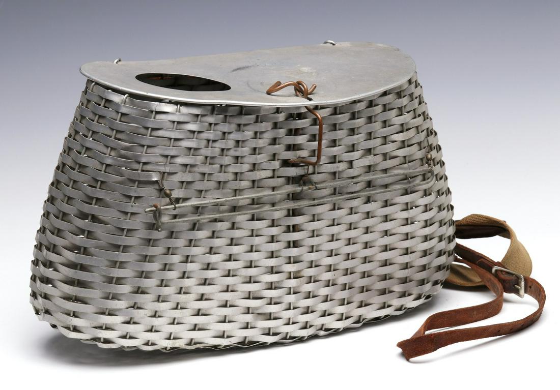 A RARE AND UNUSUAL ALUMINUM FISHING CREEL: The mid-20th century woven aluminum body, hinged aluminum lid, leather and canvas strap with buckles, no markings found. Measures 9 x 14 x 5.75 inches. We happily provide seamless in-house packing and