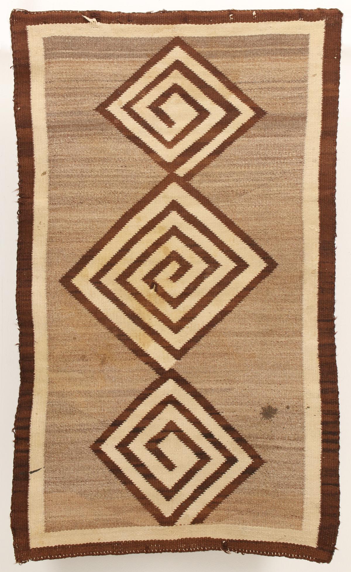 A NAVAJO RUG WITH THREE MAZE-LIKE MEDALLIONS: The simple three-color design with two borders and variegated field floating three diamonds, each woven as a maze and connected end-to-end. Measures 48 x 28.5 inches. We happily provide seamless in-ho