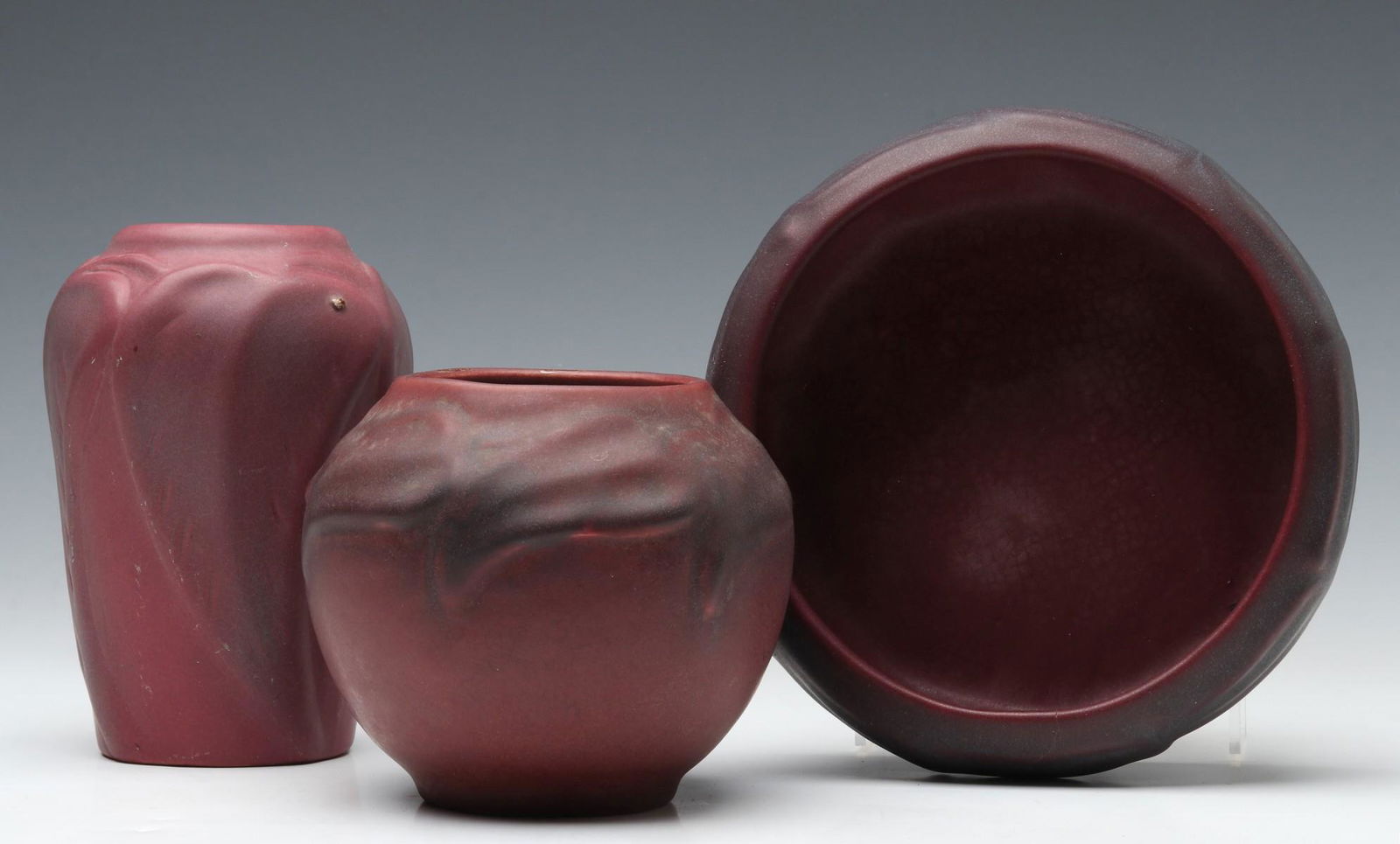 VAN BRIGGLE ART POTTERY FROM TEENS AND TWENTIES ERAS: Three Mulberry glaze examples including a USA mark bowl, 'dirty bottom' cabinet vase and circa 1930 vase, each with scratch signature underside of the base. Measures 5.75 x 3.75 and 2.5 x 7 inches. We