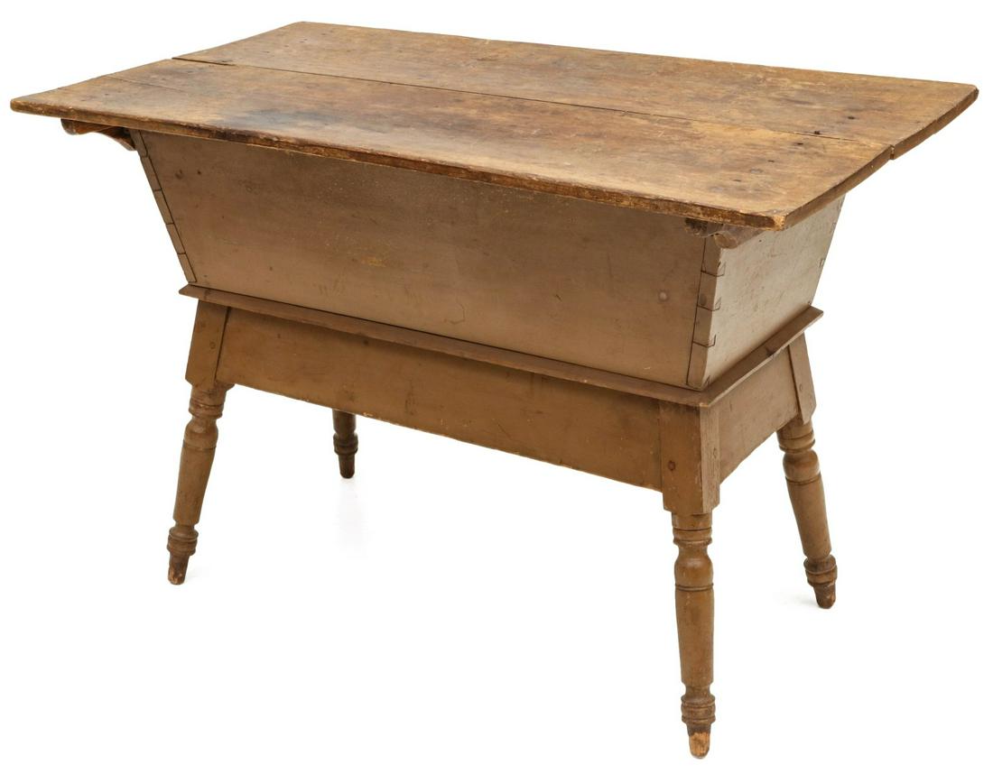A 19TH CENTURY PENNSYLVANIA PAINTED DOUGH BOX ON STAND: The scrub stop on slides overhanging a dovetailed case of canted form on base with flaring turned legs, wood peg construction, original light brown paint. Measures 29 x 24.25 x 42.75 inches. Provenanc